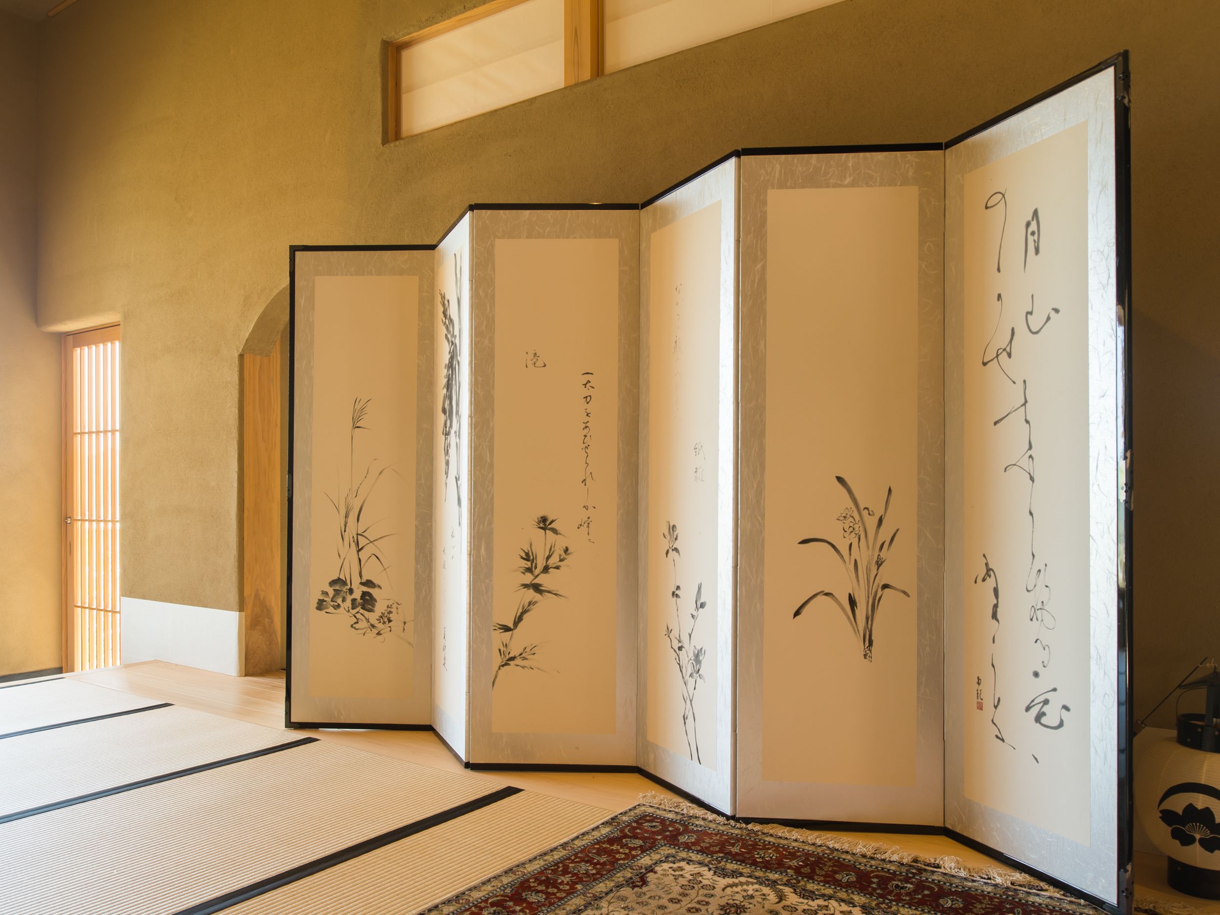 A traditional Japanese room with tatami flooring, shoji screens, and calligraphy artwork.