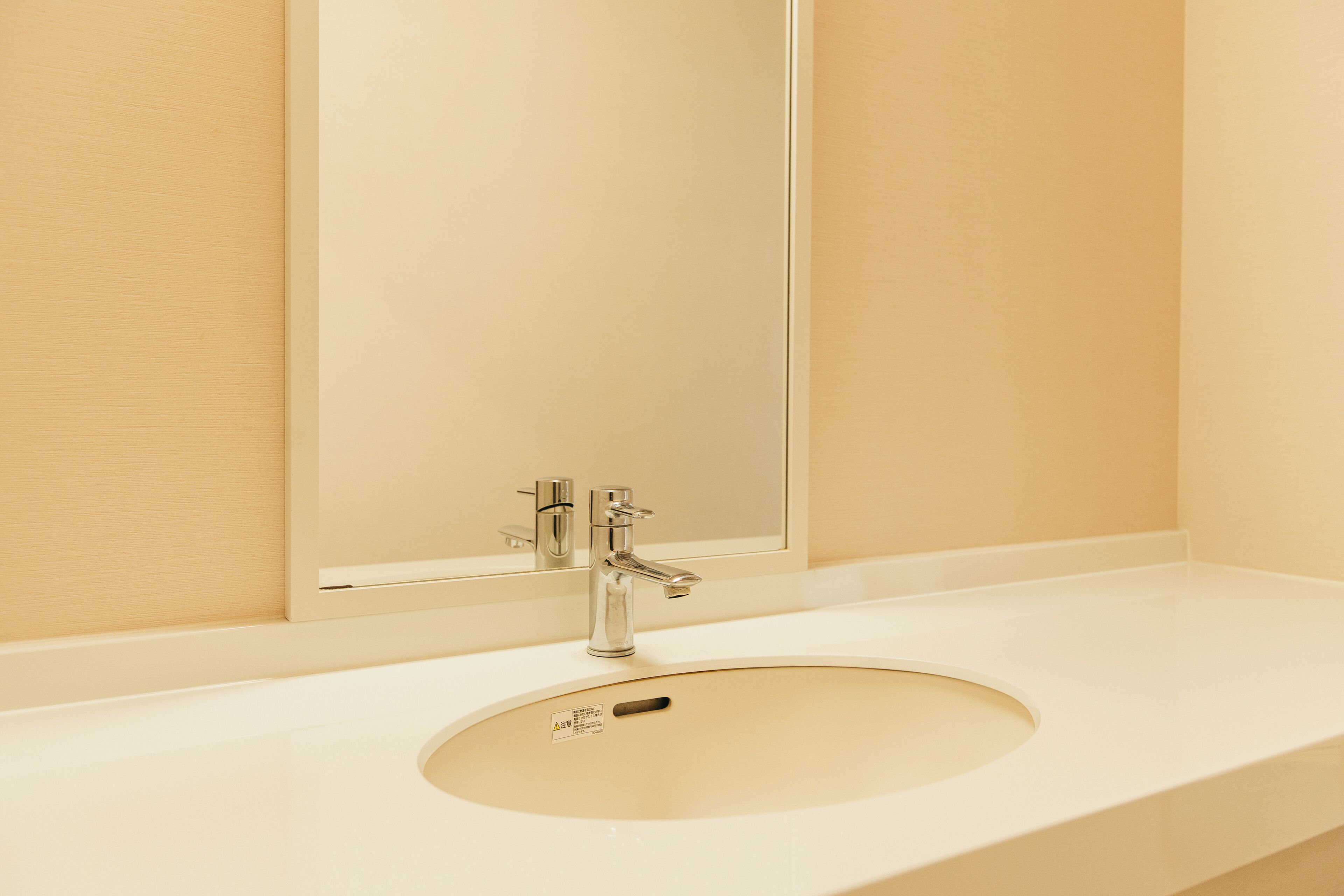 Un baño con un lavamanos blanco, un espejo y un grifo de cromo.