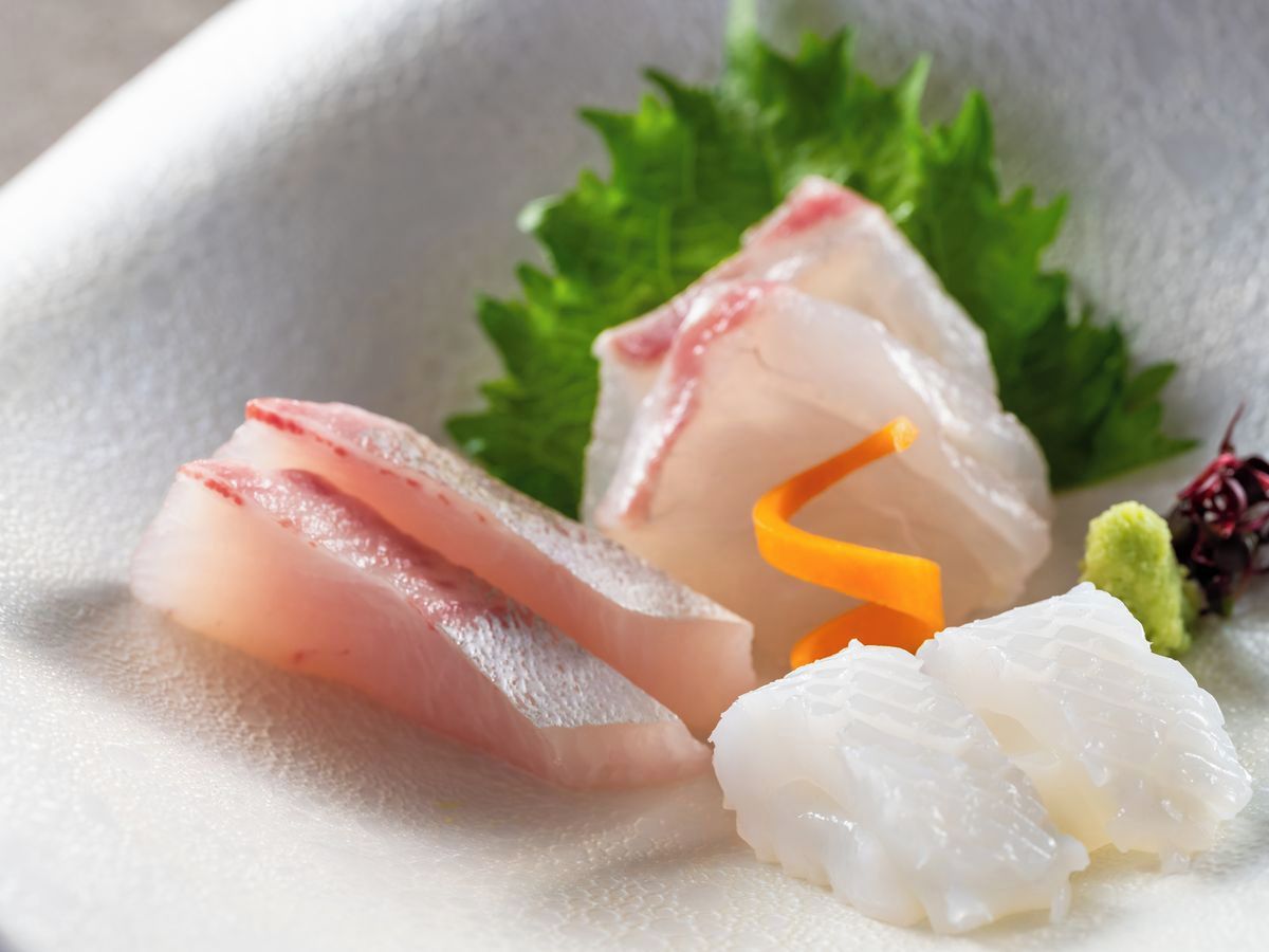 Un plato de sashimi, adornado con hojas verdes y un elemento decorativo.