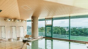 Een binnenzwembad met houten plafond en grote ramen met uitzicht over de stad.