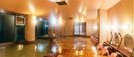 Amplio espacio interior con pisos y paredes de madera, una piscina y varios lavamanos con espejos.