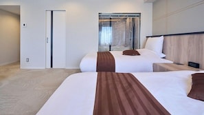 A hotel room with two beds, a sliding glass door to a balcony, and a wooden headboard.
