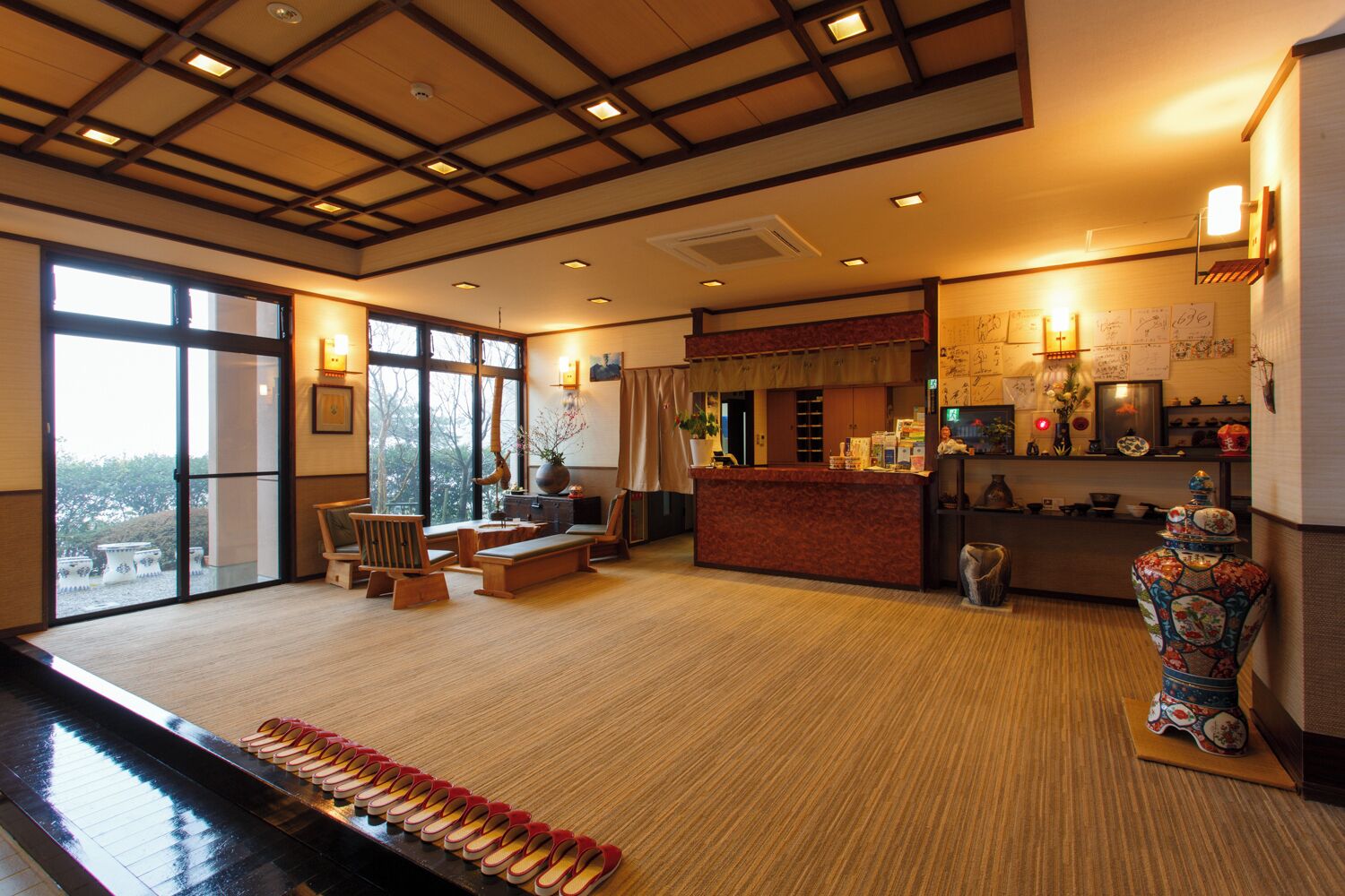 A hotel lobby with a piano, seating area, reception desk, and large windows.