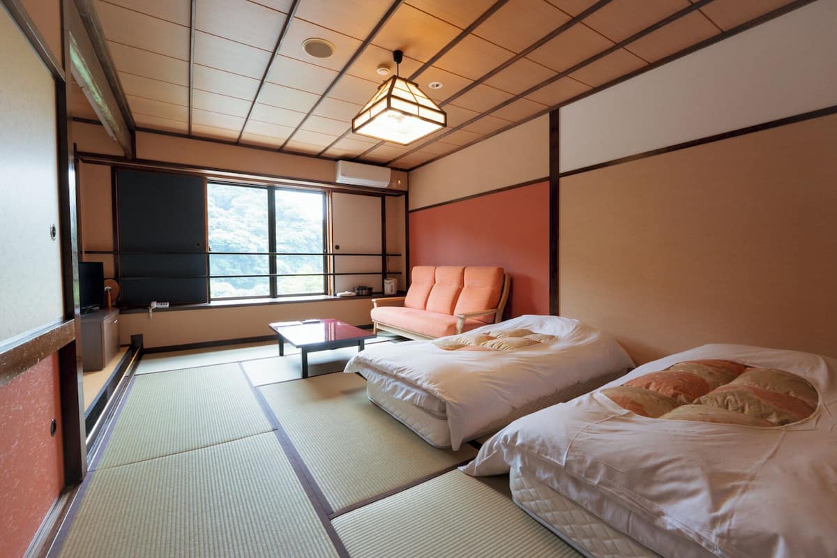 A traditional Japanese room with tatami flooring, a futon bed, a low table, and a television.