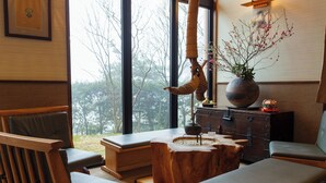Um interior moderno com mobiliário de madeira, uma janela grande e vista para árvores.