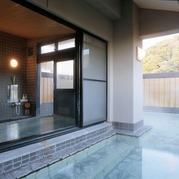 A spa area with a glass-enclosed hot tub, a shower, and a view of the outdoors.
