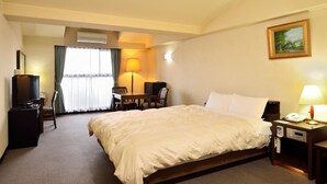 Une chambre d’hôtel comprenant un lit, un bureau avec une chaise, une télévision, une lampe et un tableau au mur.