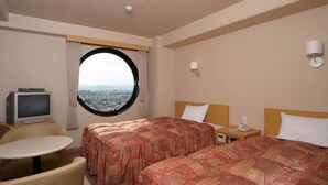 A hotel room with two beds, a TV, a round window, and a view of the city. - Hotel Peaceful (Kumamoto)