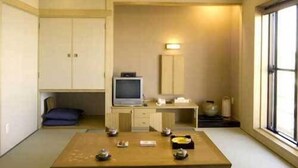 A traditional Japanese-style room with tatami flooring, a low table with cushions, a television, and a sliding door. - Hotel Ayase (Rishifuji)