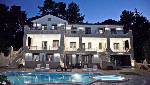 Un bâtiment à deux étages doté d’une piscine, d’un espace extérieur aménagé et d’une façade en pierre.