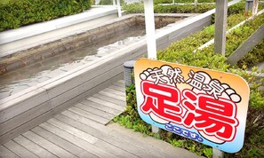 A wooden boardwalk leading to a body of water, with a sign in a foreign language.