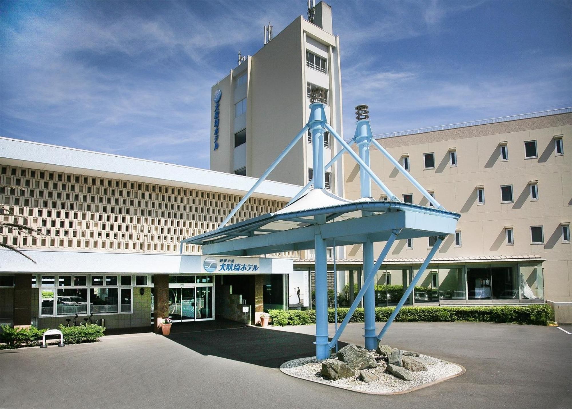 A hotel with a modern facade, a prominent blue structure in the center, and a sign indicating a wedding hotel.