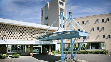 A hotel with a modern facade, a prominent blue structure in the center, and a sign indicating a wedding hotel.