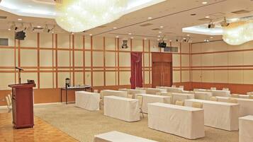 A conference room with a podium, tables, chairs, and a large chandelier.