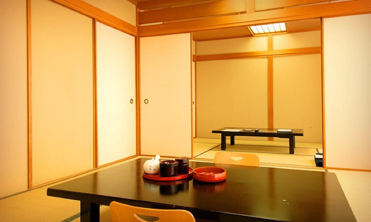 A traditional Japanese-style room with tatami flooring, a low table with a tea set, and sliding doors.