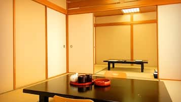 A traditional Japanese-style room with tatami flooring, a low table with a tea set, and sliding doors.