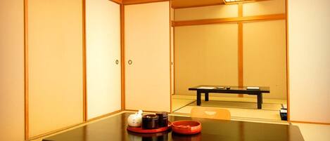 A traditional Japanese-style room with tatami flooring, a low table with a tea set, and sliding doors.