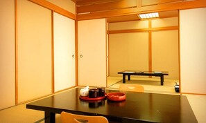Una habitación tradicional japonesa con suelo de tatami, una mesa baja con juego de té y puertas correderas.