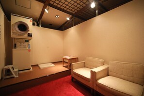 Una habitación con lavadora, una mesita, dos sillas y una alfombra roja.