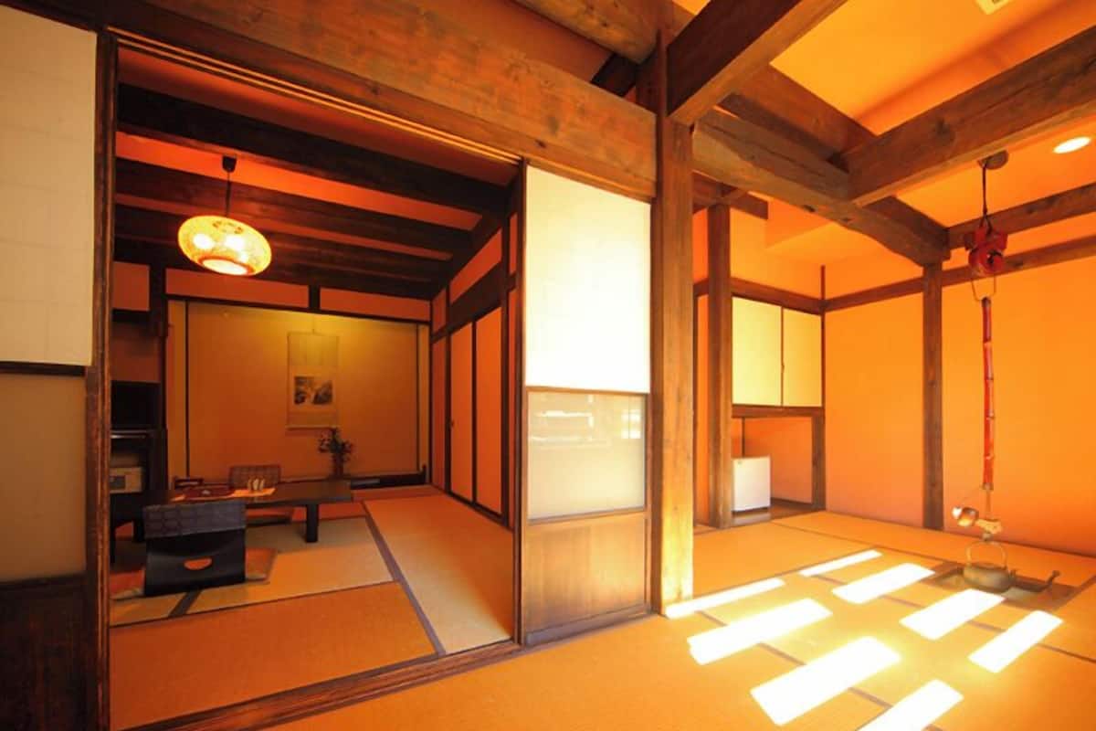 A traditional Japanese room with tatami flooring, sliding doors, and a low ceiling with exposed beams.