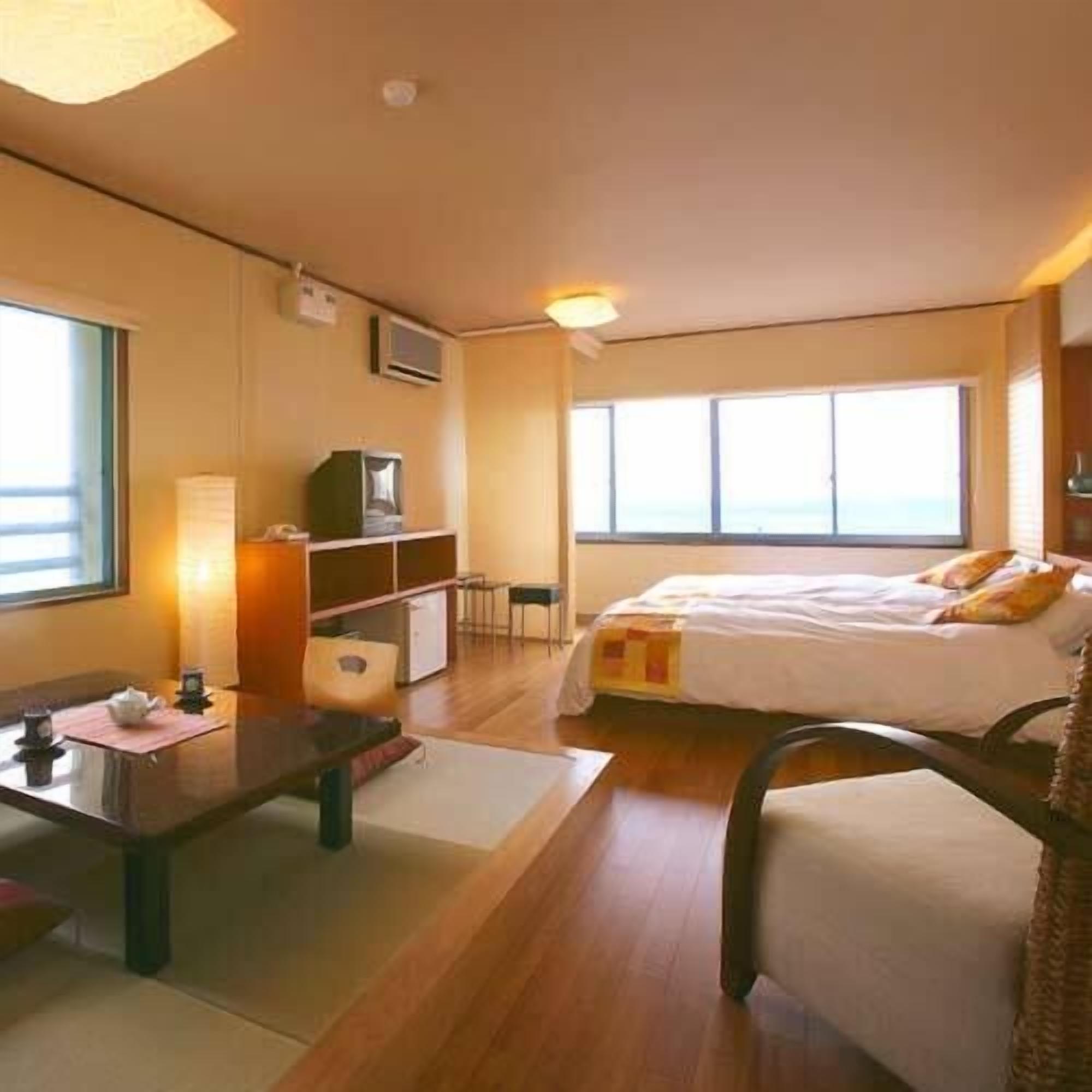 Habitación de hotel con cama, escritorio, silla, mesita, televisor y ventana.