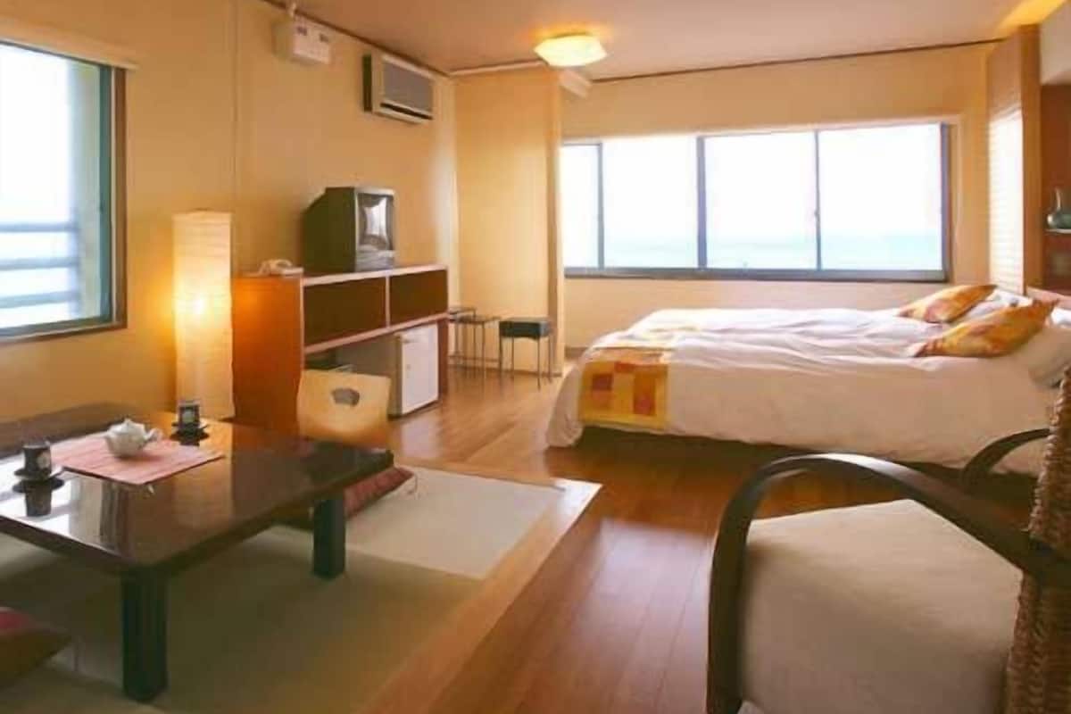 Ein Hotelzimmer mit Bett, Schreibtisch, Stuhl, Fernseher und Fenster.