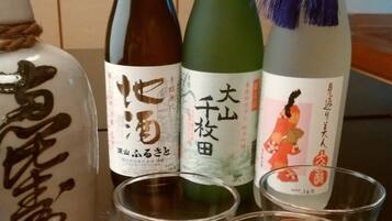 Four bottles of Japanese sake and three shot glasses on a wooden tray.