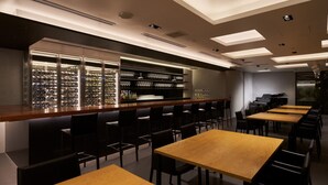 A modern bar area with a long counter, shelves with glasses, and a piano. There are multiple tables and chairs arranged for dining. - Hotel Royal Garden Kisarazu (Kisarazu)