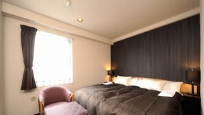 A hotel room with a large bed, a bedside table with a lamp, a chair with a table, and a window with curtains. - Hotel Royal Garden Kisarazu (Kisarazu)