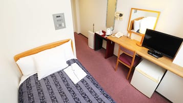 A hotel room with a bed, a desk with a computer, a mirror, and a small refrigerator.