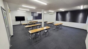 A classroom with desks, chairs, a whiteboard, a TV, and a projector screen. - Hotel Royal Garden Kisarazu (Kisarazu)