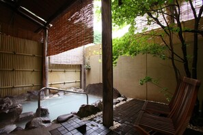 Un onsen japonés tradicional con un banco de madera, una bañera de piedra y paredes de bambú.
