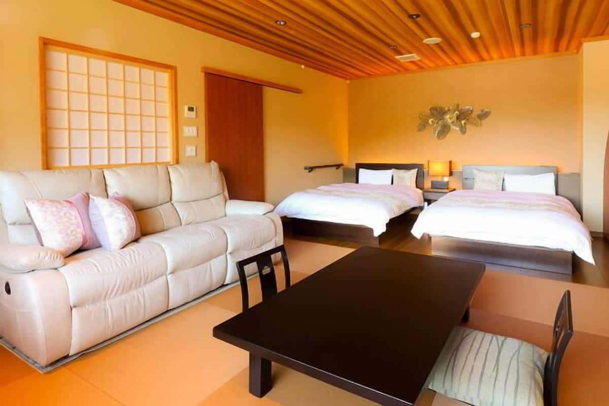 Habitació d'hotel amb un sofà, dos llits, una taula i una decoració mural.