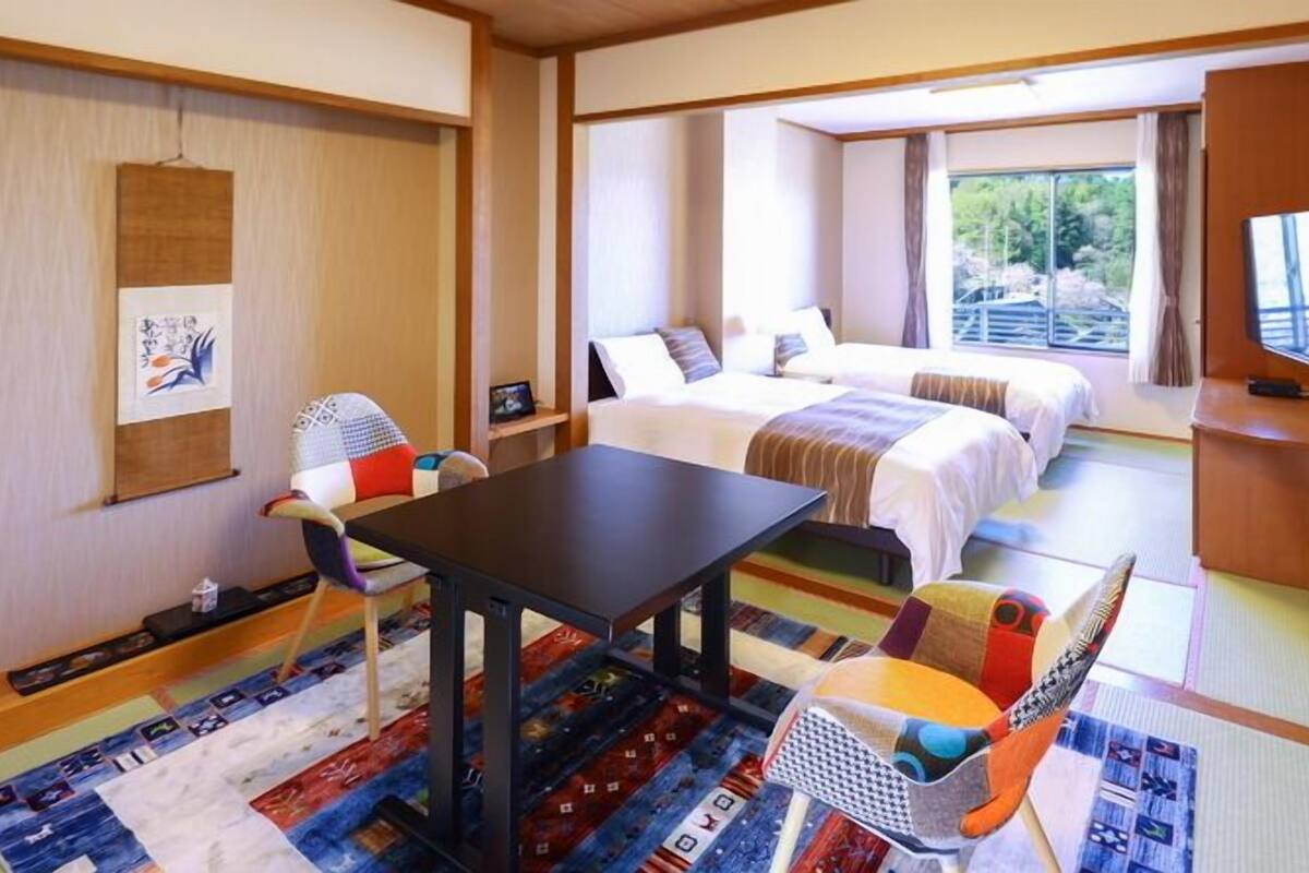 Una habitació d'hotel amb un llit, una taula de treball, una cadira i una televisió.