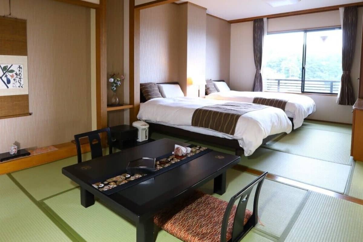 Habitació japonesa tradicional amb fusteria de tatami, un llit futón, una taula baixa amb safata i una prestatgeria penjada a la paret.