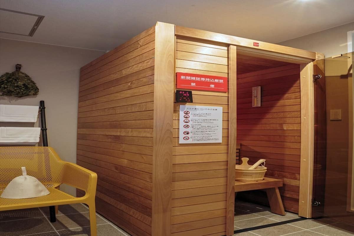 A sauna room with a wooden door, a bench, and a towel rack.