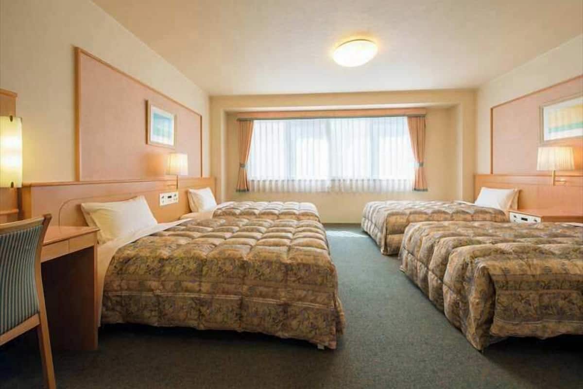 A hotel room with two beds, a desk, and a chair.