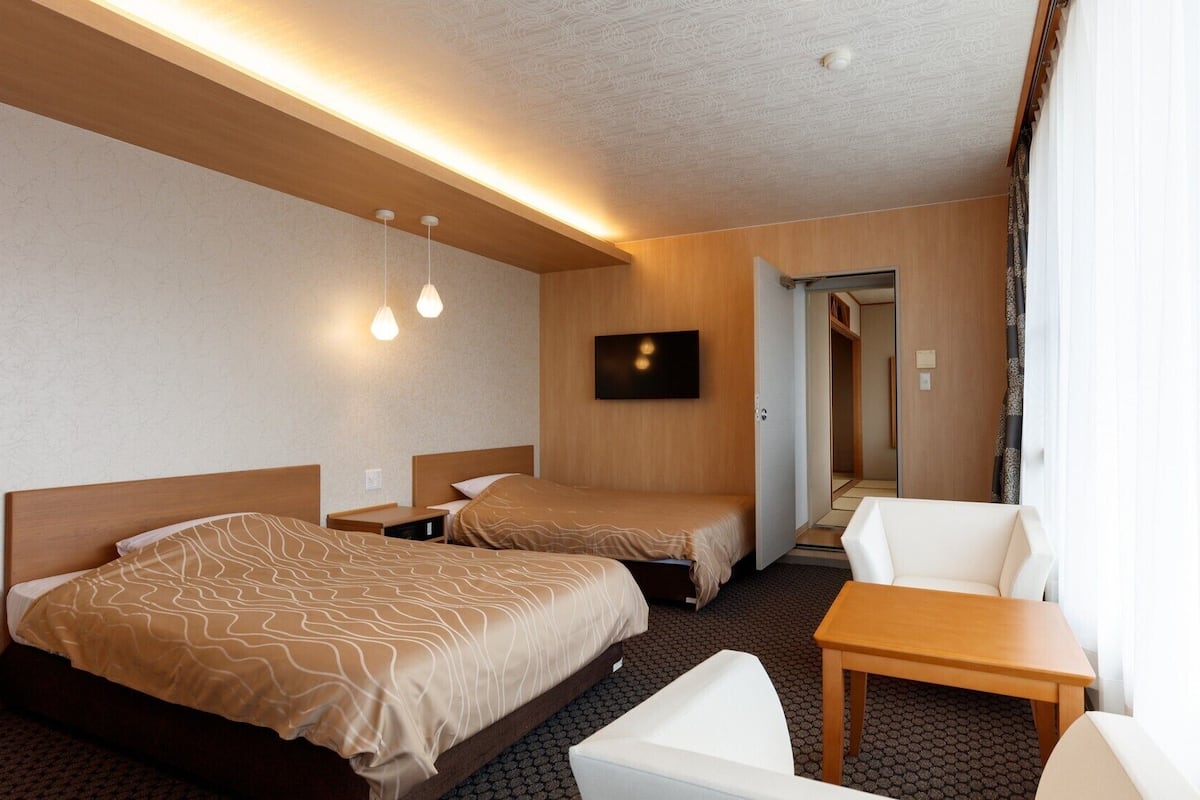 Une chambre d’hôtel avec deux lits, une télévision, une petite table et une chaise.