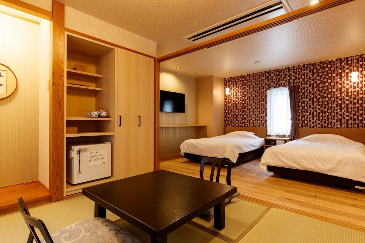 Une chambre de style japonais traditionnel, comprenant deux lits, une télévision, une petite table et une armoire.
