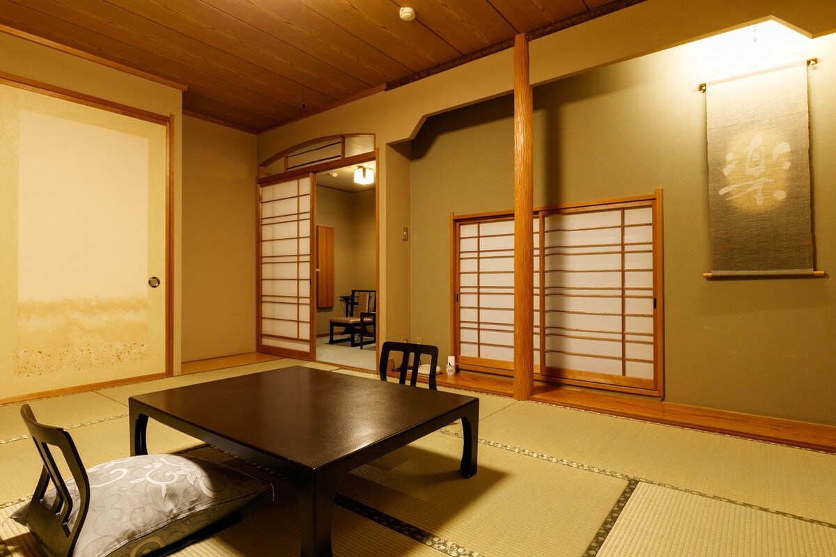 A traditional Japanese room with tatami flooring, a low table, and sliding doors.