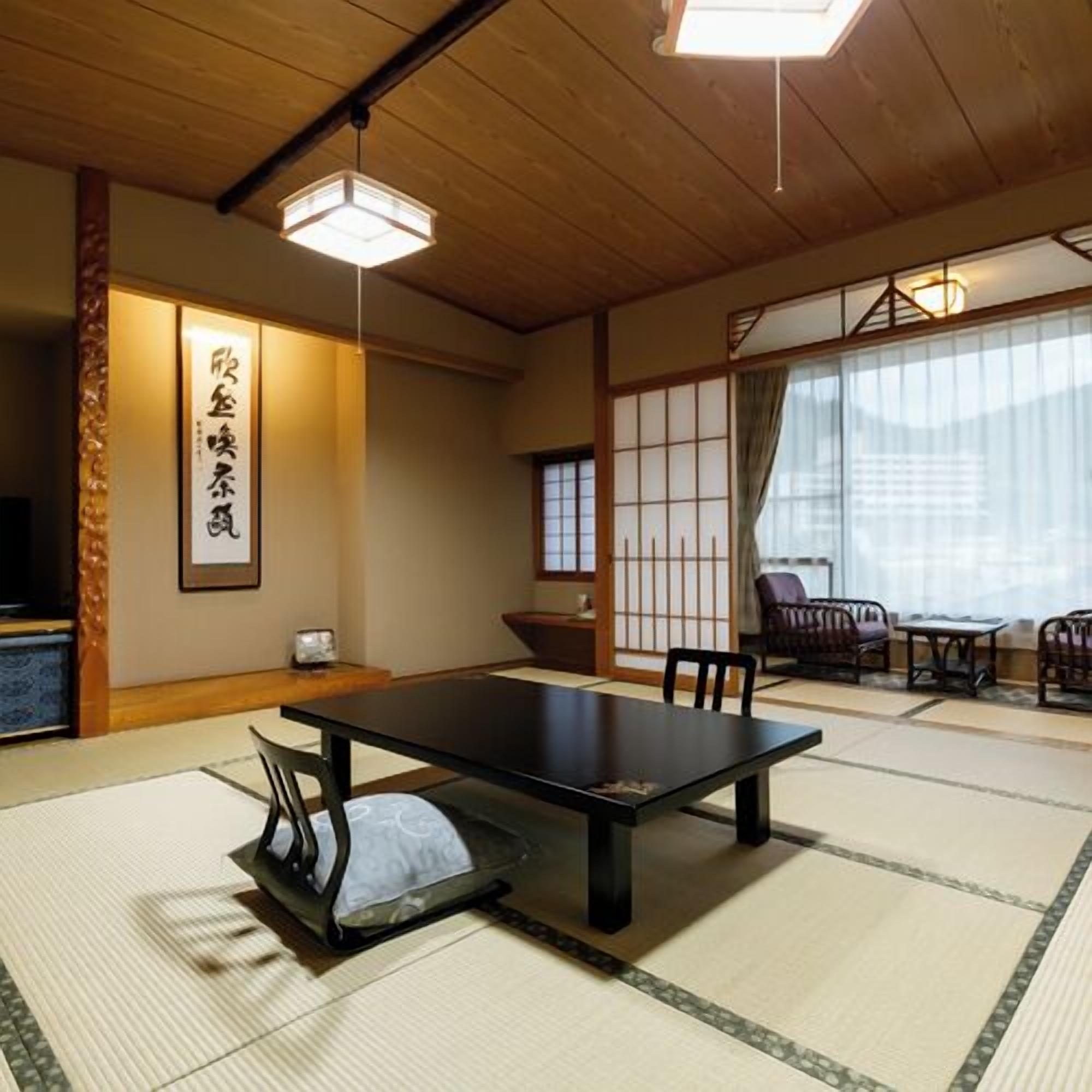 A traditional Japanese room with tatami flooring, a low table, chairs, and sliding doors.