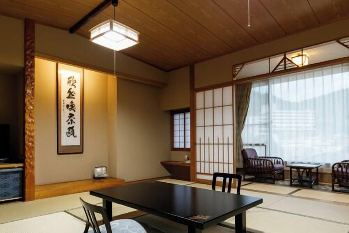 A traditional Japanese room with tatami flooring, a low table, chairs, and sliding doors.