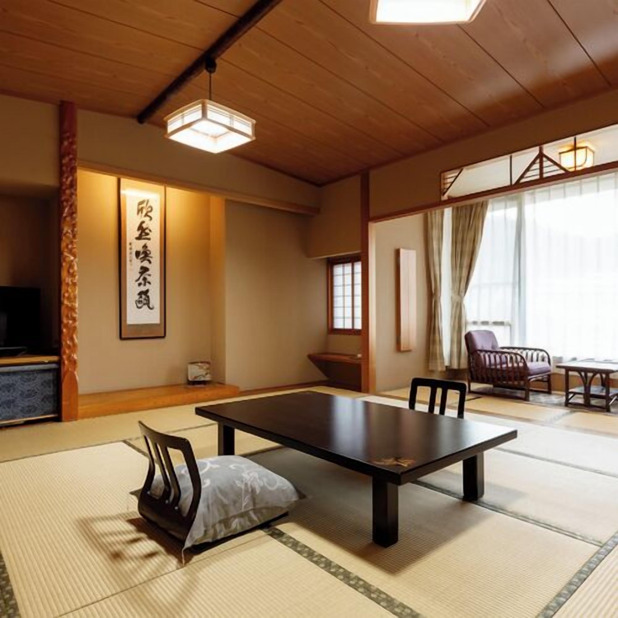 A traditional Japanese room with tatami flooring, a low table, chairs, a television, and a sliding door.