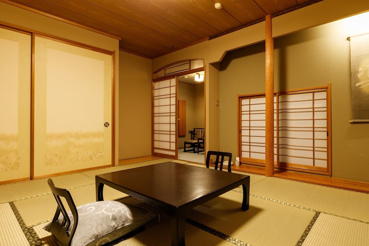 Une pièce de style japonais traditionnel, avec un sol recouvert de tatamis, une table basse et des portes coulissantes.