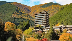 A multi-story hotel with a traditional architectural style, surrounded by autumn-colored trees and mountains. - Shogetsu (Gero)