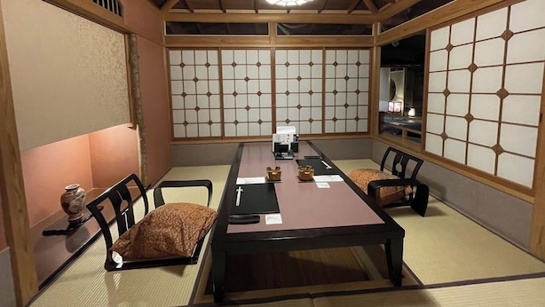 A traditional Japanese-style room with tatami flooring, shoji screens, a low ceiling with wooden beams, and a central table with chairs. - Shogetsu (Gero)