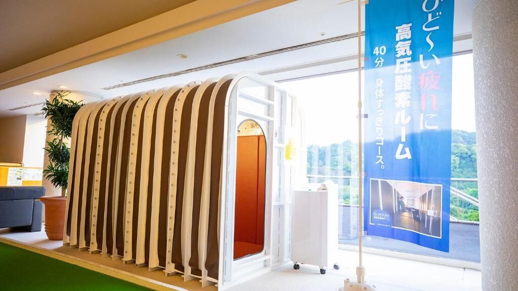 A modern hotel interior with a unique, curved wall structure, a large window offering a view, and a blue banner with text.