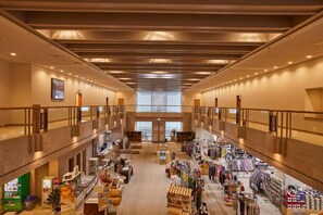 A spacious indoor shopping area with multiple levels, retail stores, and a central staircase. - KAMOGAWA COUNTRY HOTEL (Kamogawa)