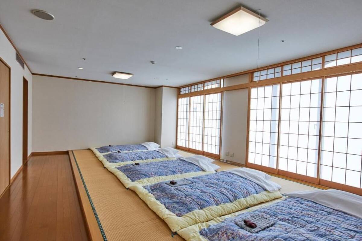 A traditional Japanese room with tatami flooring, shoji screens, and a futon bed.