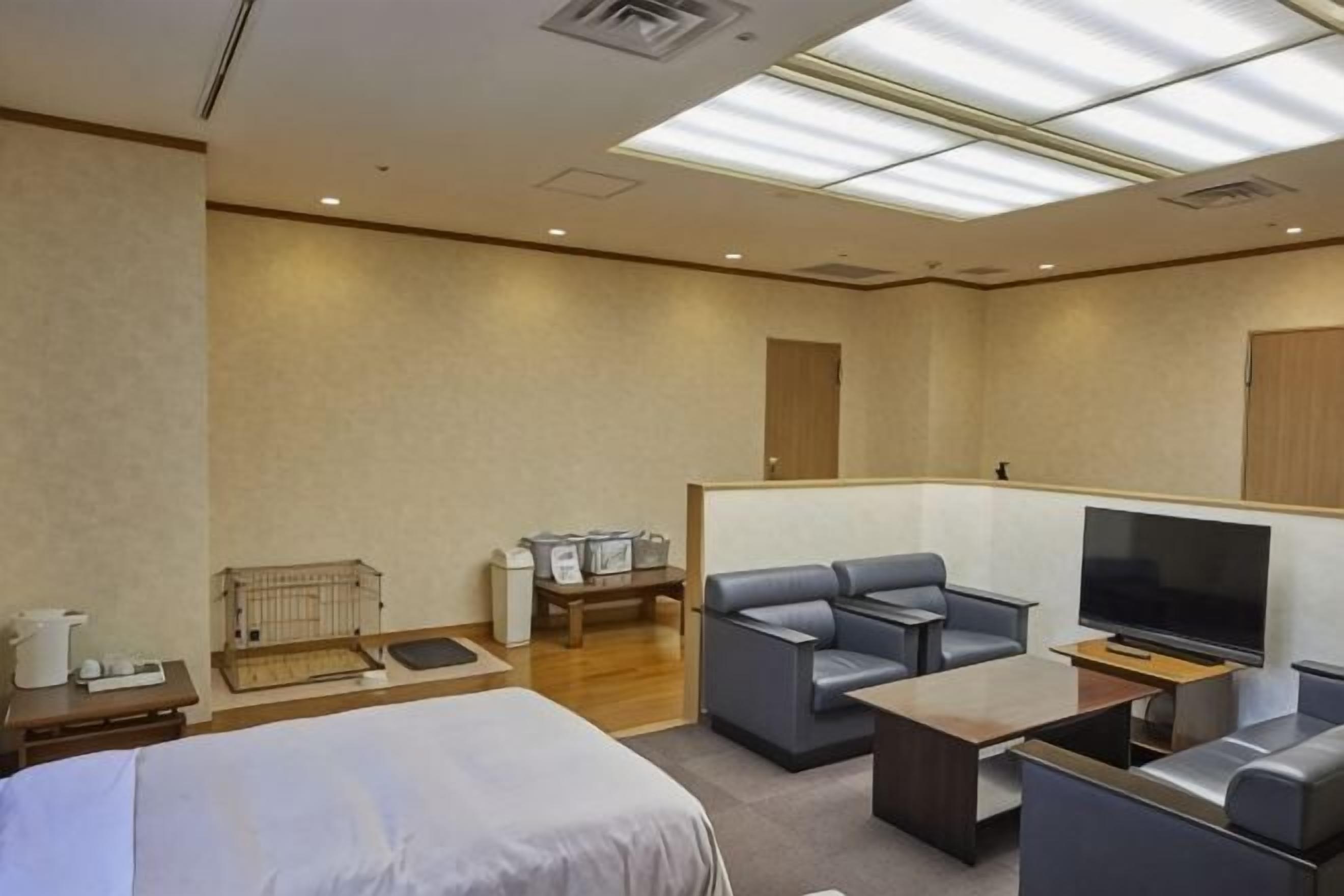 A hotel room with a bed, a TV, a sofa, a coffee table, and a desk.
